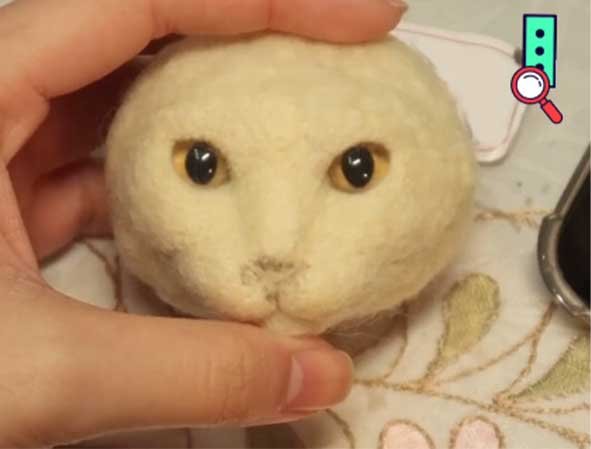Detailed base for a custom needle felted cat sculpture showing firm wool head structure and realistic glass eye placement.