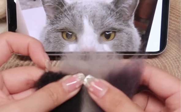 Hand-blending dark gray and black wool into a gray base to create a mottled, realistic fur effect for a custom needle felted pet sculpture.