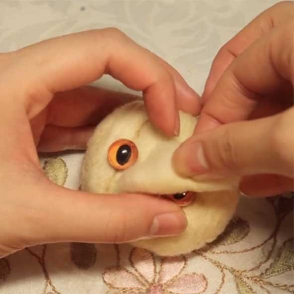 Applying upper eyelids to a custom needle felted cat using a No. 40 needle, covering the top 1/4 of the glass eye for a realistic expression.
