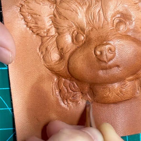 Hand-carving process of customized pet gifts on wet vegetable tanned leather showing blade resistance and fiber texture