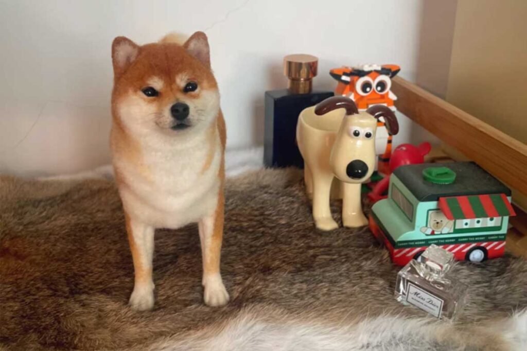 A 3D lifelike needle felted Shiba Inu sculpture standing alongside personal decor items, creating a sensory memory container.