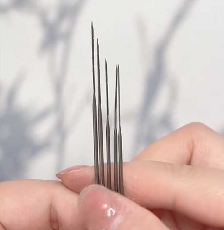 Professional needle felting tools held in hand, featuring fine 40-gauge needles for high-density 3D wool sculpting.