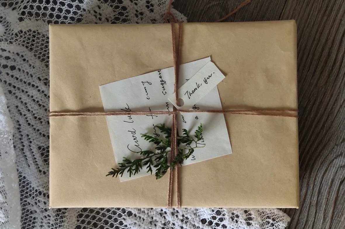 Minimalist brown paper wrapped gift for pet lovers featuring rustic twine, a green sprig, and handwritten thank-you notes, representing unique and handmade pet gift ideas.