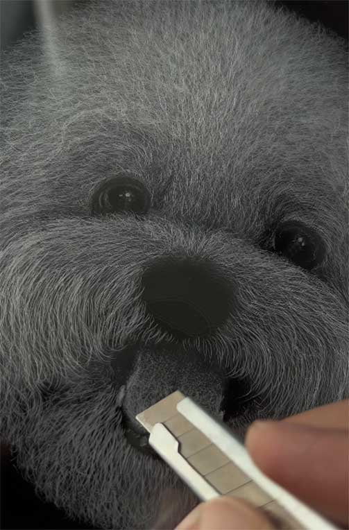 Artist using a precision blade to hand-carve a 3D pet portrait on acrylic, highlighting the artisanal process of creating gifts for dog lovers.