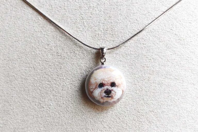 Authentic hand-painted Bichon Frise pet portrait necklace on natural pearl base, showcasing fine brushstrokes and artistic detail.