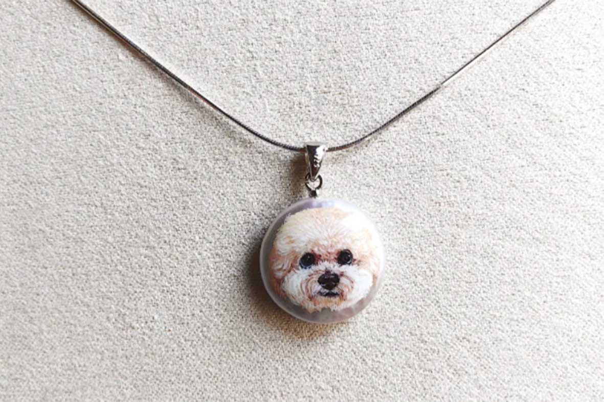 Authentic hand-painted Bichon Frise pet portrait necklace on natural pearl base, showcasing fine brushstrokes and artistic detail.
