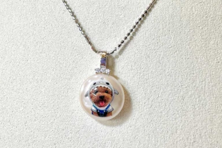 Custom handmade pet necklace featuring a miniature hand-painted poodle portrait on a pearl-like pendant with a silver chain.