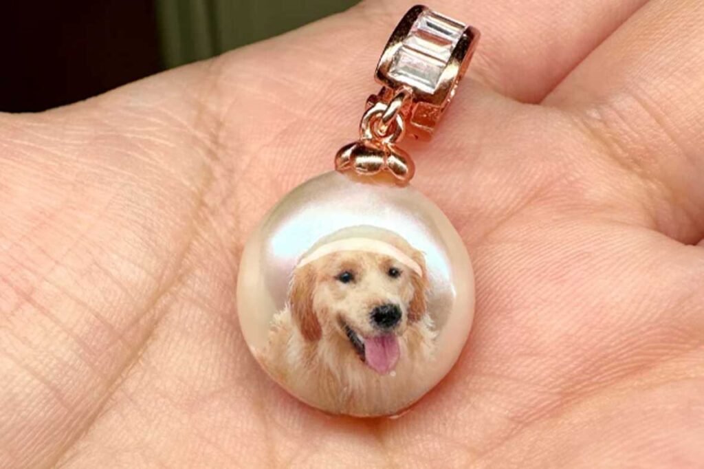 Close-up of a custom golden retriever pet portrait pendant held in hand, showing fine hand-painted textures and rose gold setting.